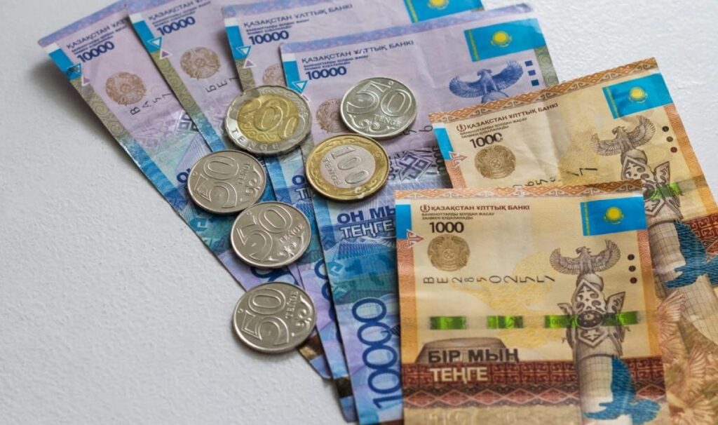 Тенге - монеты и банкноты - лежат на столе