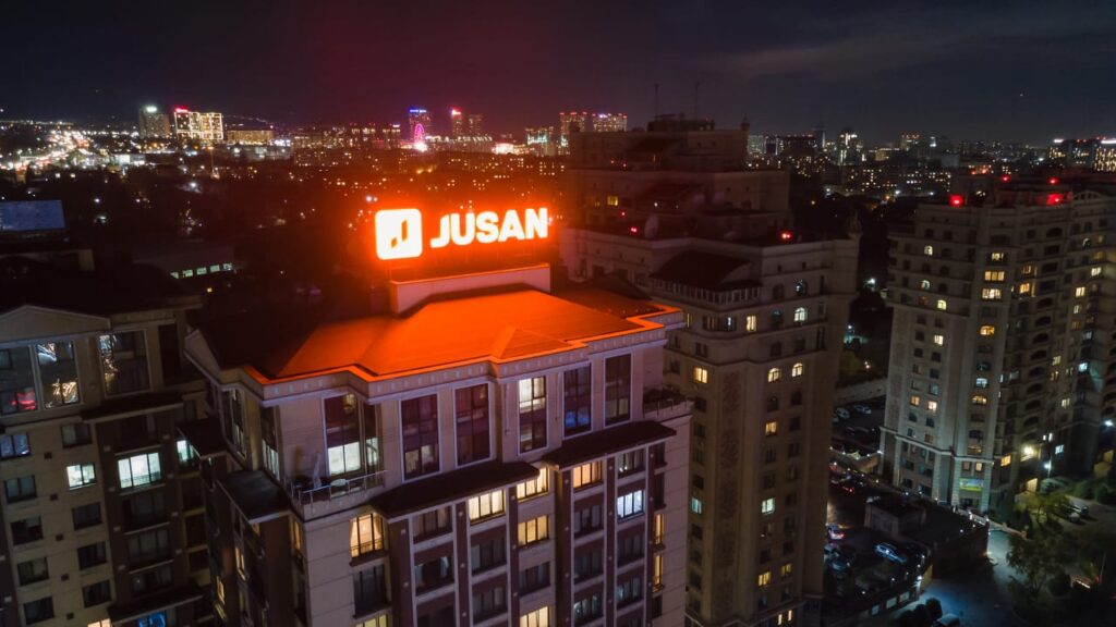 Вывеска Jusan Bank горит ночью на здании