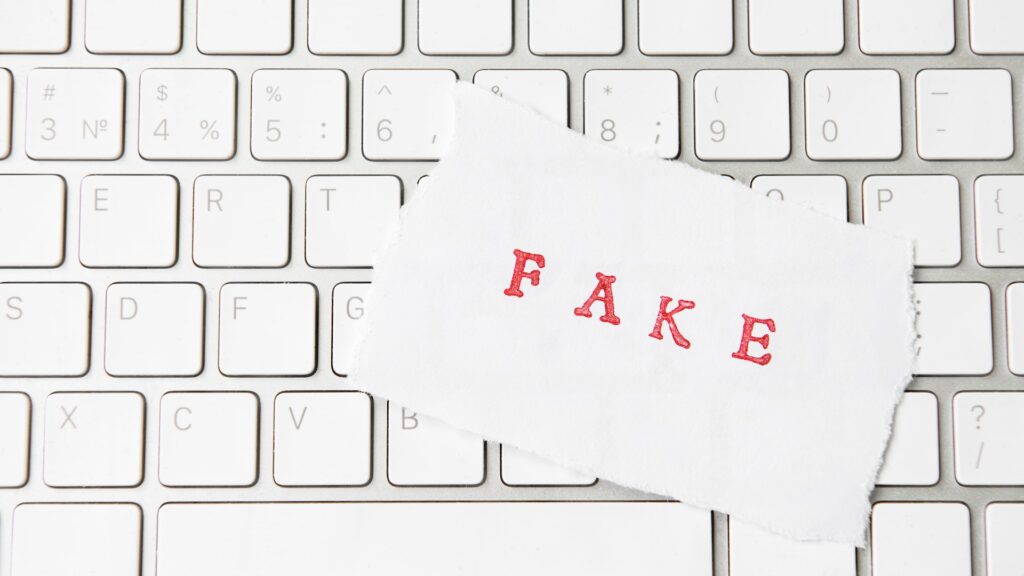 Листок с надписью Fake лежит на клавиатуре