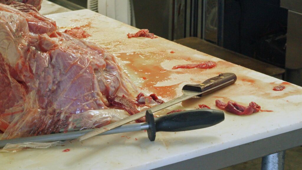 Мясо лежит на полке рядом с ножами