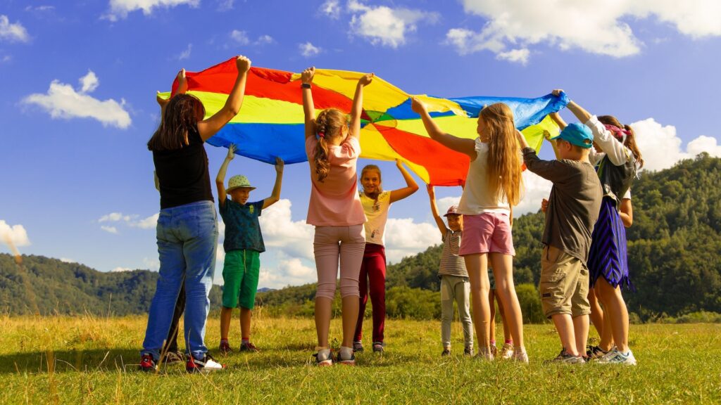 Дети радужно играют на полянке летом