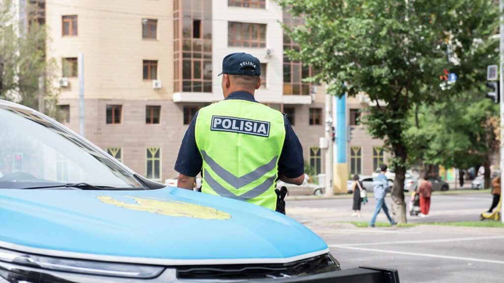 Сотрудник полиции стоят рядом с служебным автомобилем