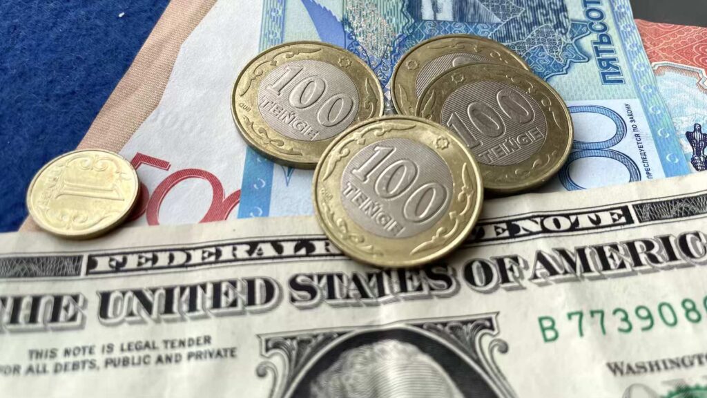 Купюры и монеты тенге в перемешку с долларами