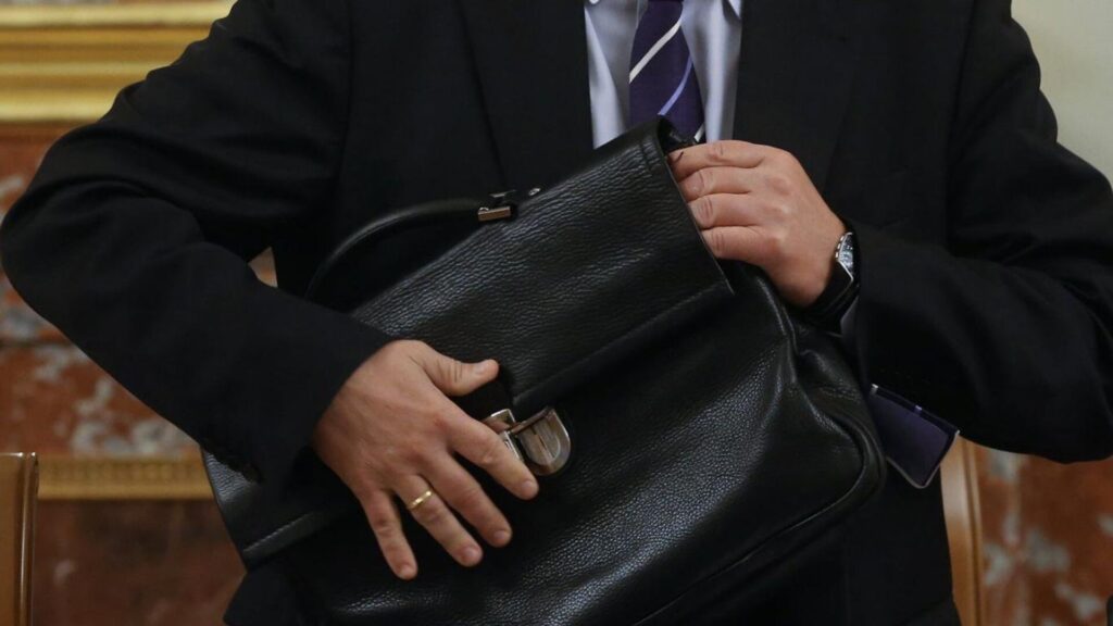 Человек в костюме держит портфель с документами