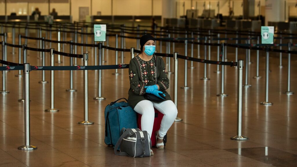 Человек в аэропорту в маске и перчатках из-за пандемии