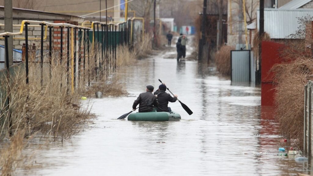 Двое людей гребут на лодке при наводнении