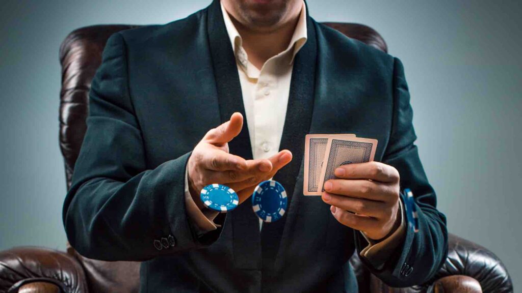 Мужчина в костюме с картами в руках кидает игровые фишки