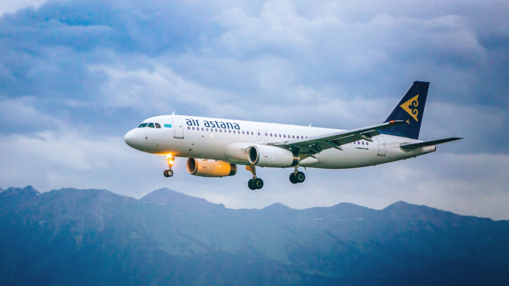 Самолет авиакомпании Air Astana в небе на фоне гор