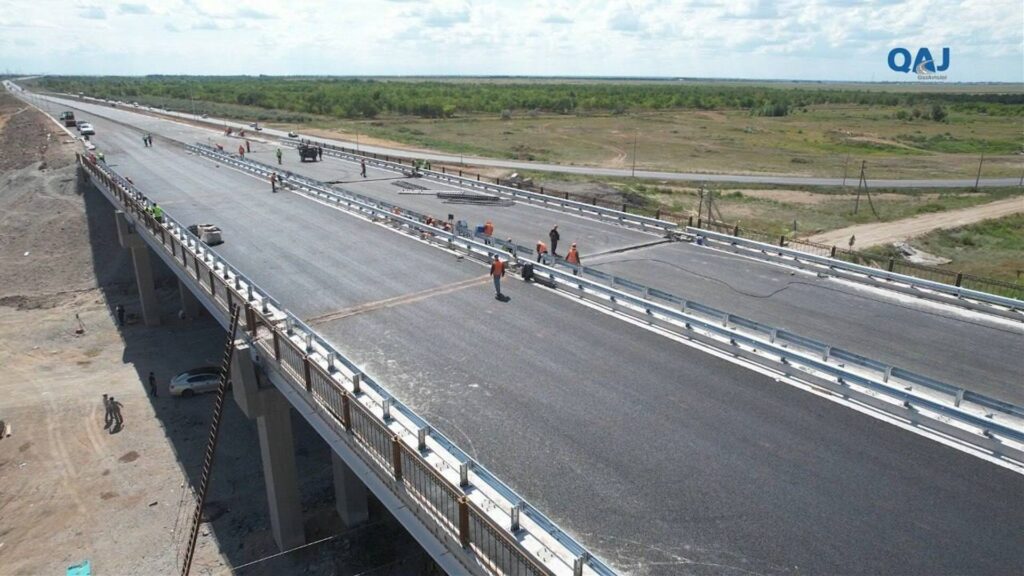 Рабочие укладывают асфальт на новом дорожном мосту