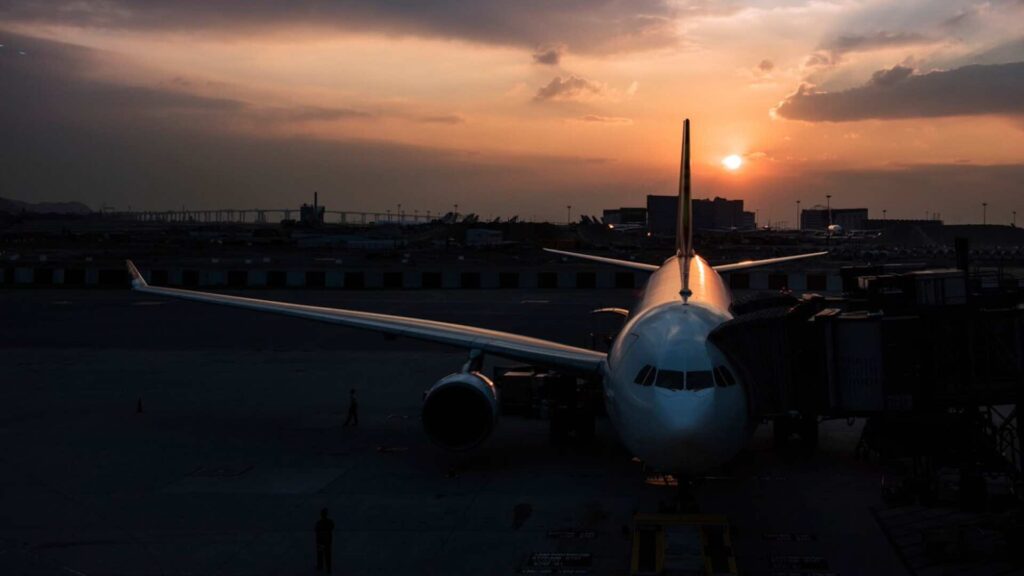 Самолет стоит в аэропорту на фоне заката солнца