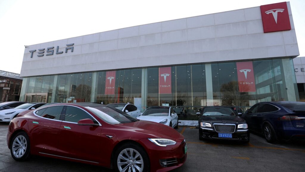 Автомобиль Tesla проезжает мимо магазина производителя электромобилей (EV) в Пекине, Китай