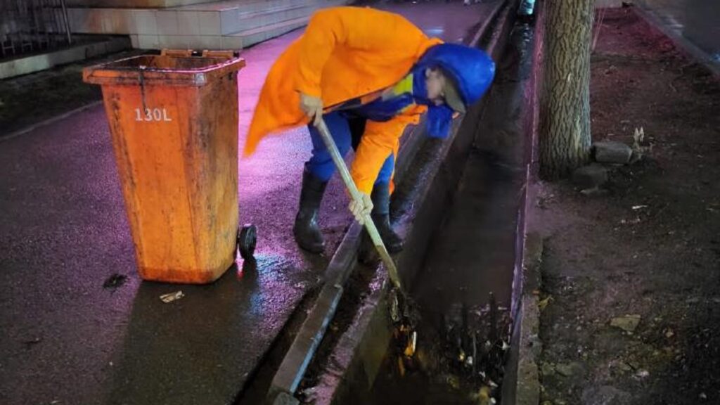 Работник чистит арык под дождем