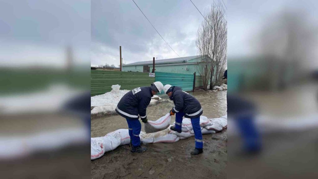 Двое рабочих кладут мешки на землю от паводков