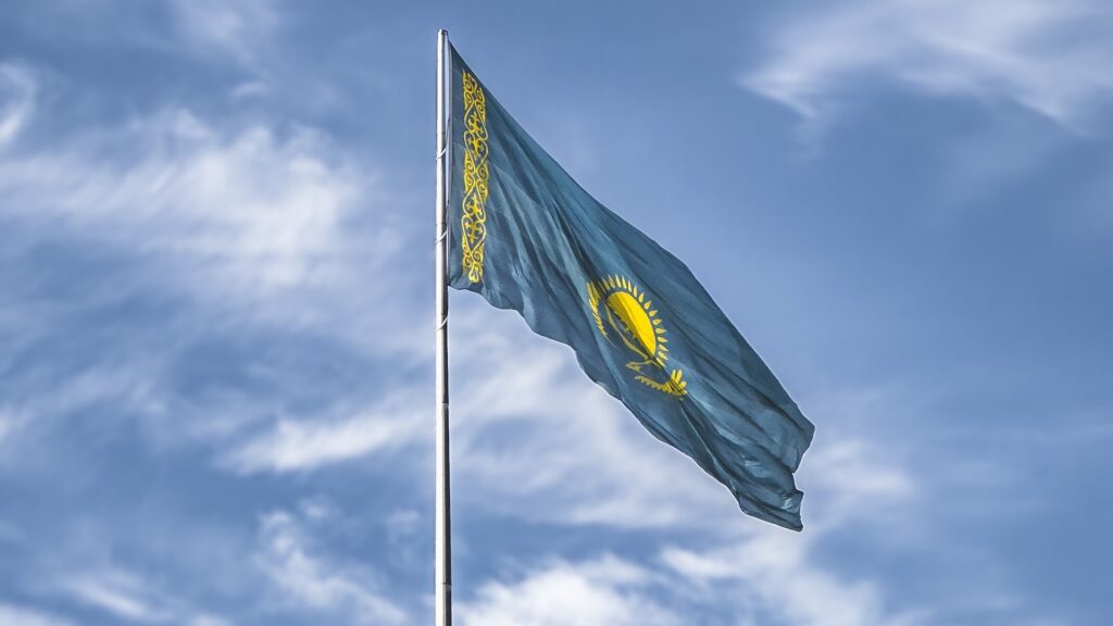 Флаг Казахстана развивается на фоне синего ясного неба