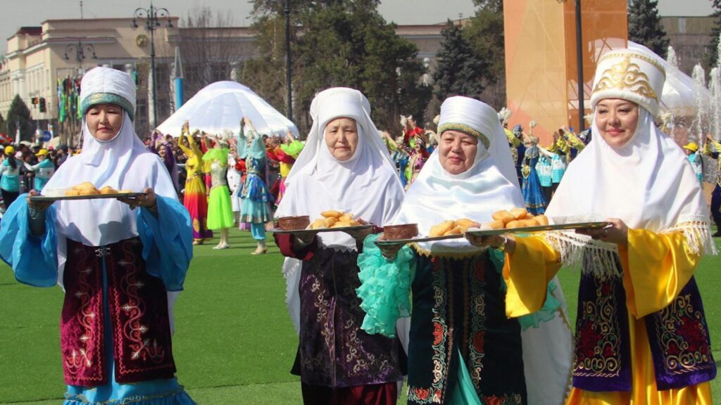 Женщины в национальных нарядах на праздновании Наурыза с баурсаками и кумысом