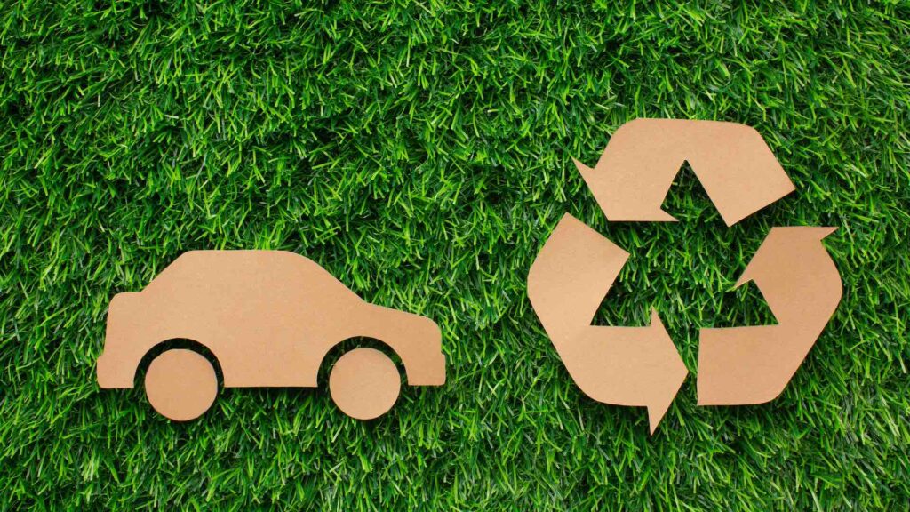 Картонные значки автомобиля и переработки на зеленой траве