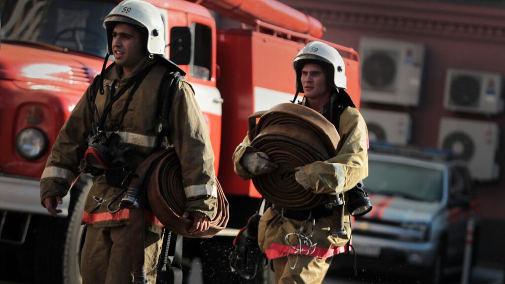 Двое пожарных несут оборудование