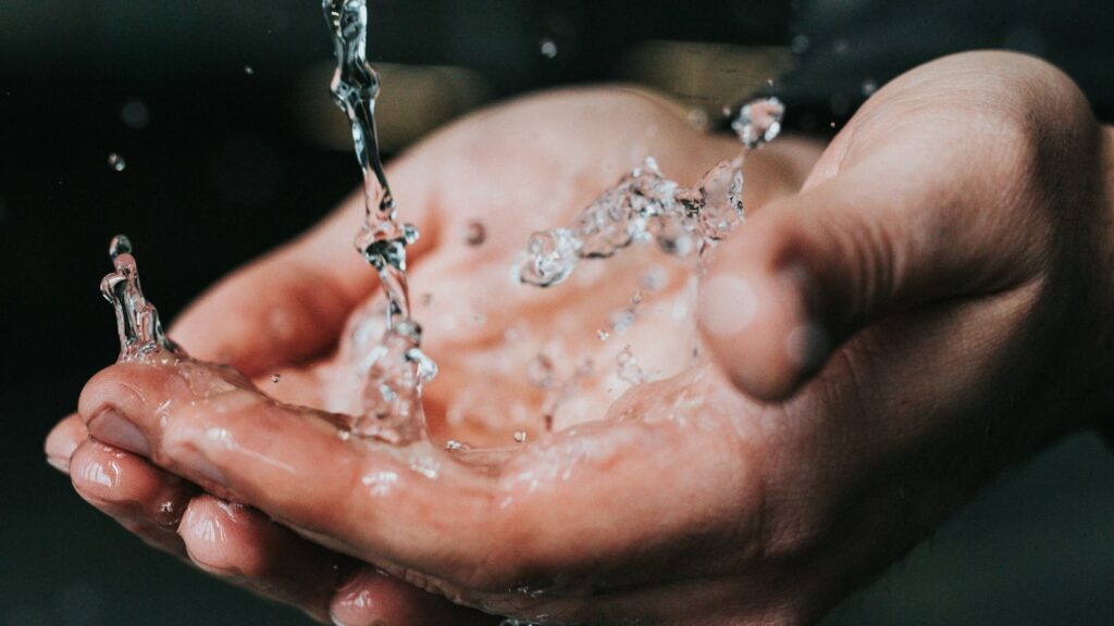 На руки человека бежит чистая питьевая вода