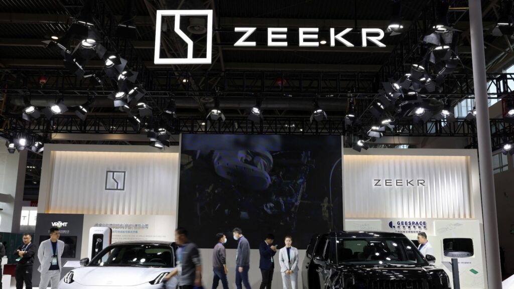 Люди проходят мимо стенда Zeekr, премиального бренда электромобилей (EV) китайского автопроизводителя Geely, в торговом центре в Пекине, Китай