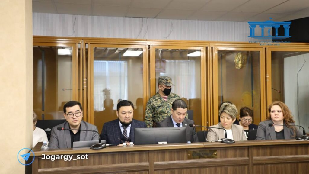 Адвокаты Бишимбаева сидят за столом но фоне кабинки, где сидит сам Бишимбаев