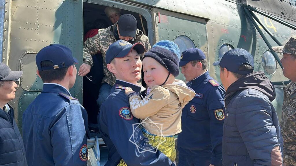Спасатель с ребенком на руках возле вертолета