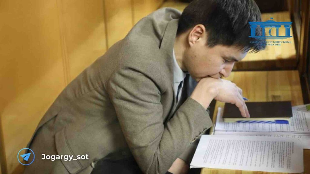 Бахытжан Байжанов читает текст на листе бумаги в суде