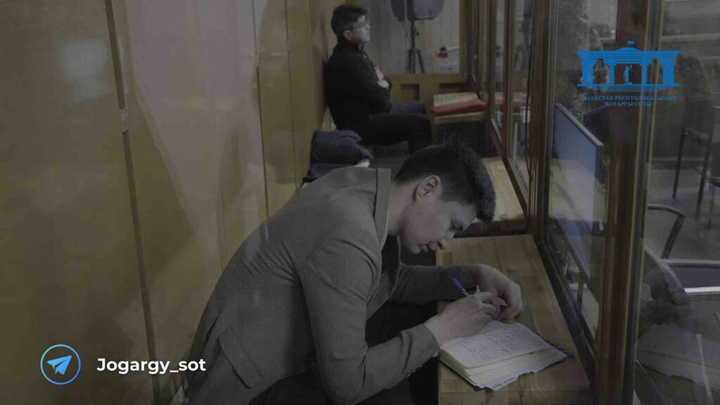 Бахытжан Байжанов пишет ручкой, Куанды Бишимбаев сидит