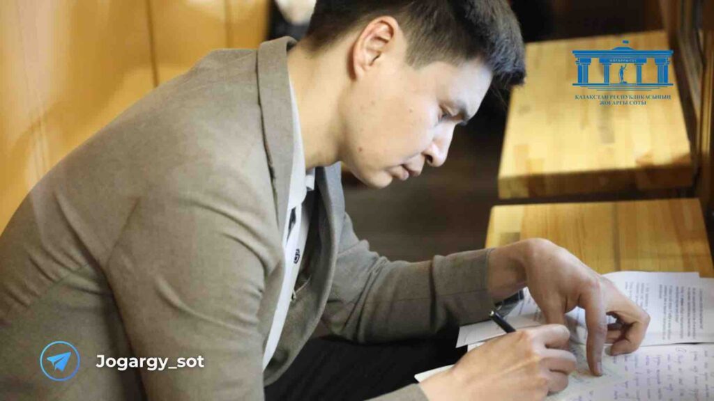 Бахытжан Байжанов пишет ручкой на бумаге на скамье подусимых