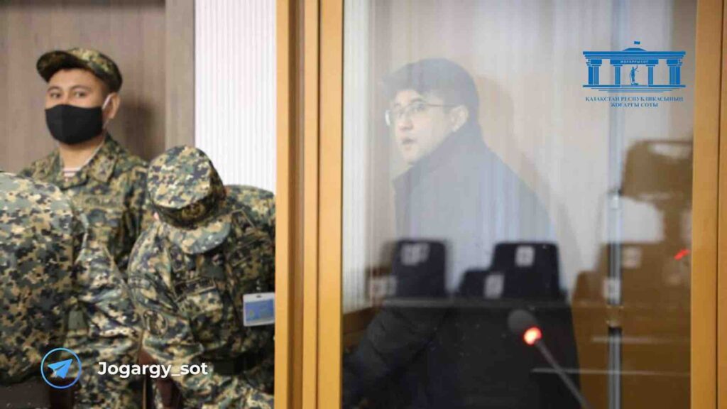 Куандык Бишимбаев за стеклом в суде рядом с военнослужащими