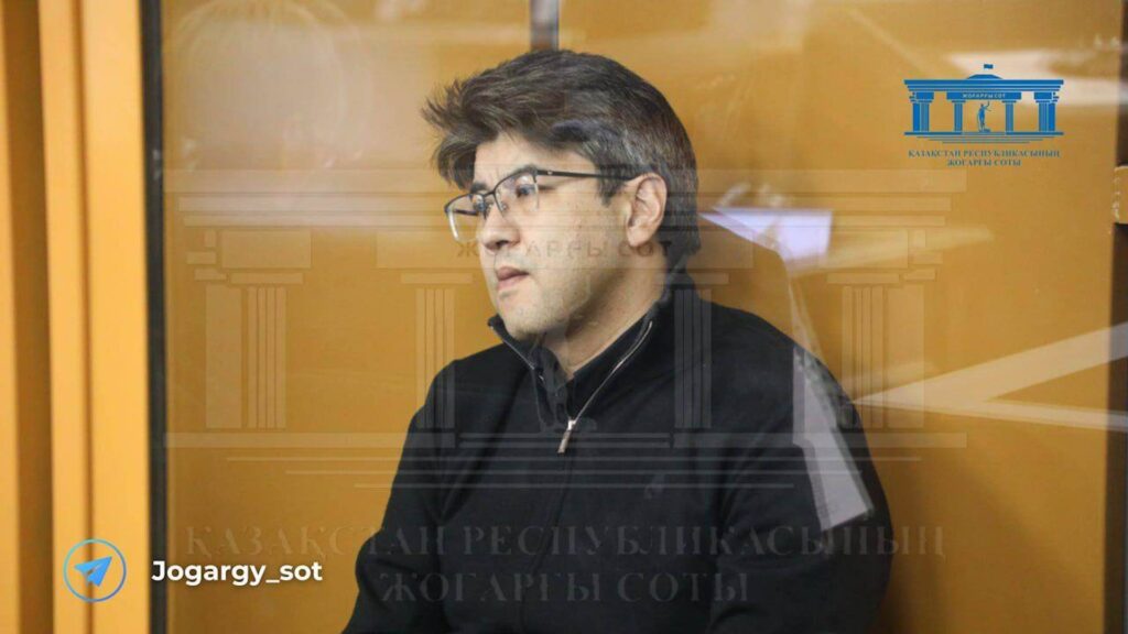 Куандык Бишимбаев в очках сидит на скамье подсудимых в зале суда
