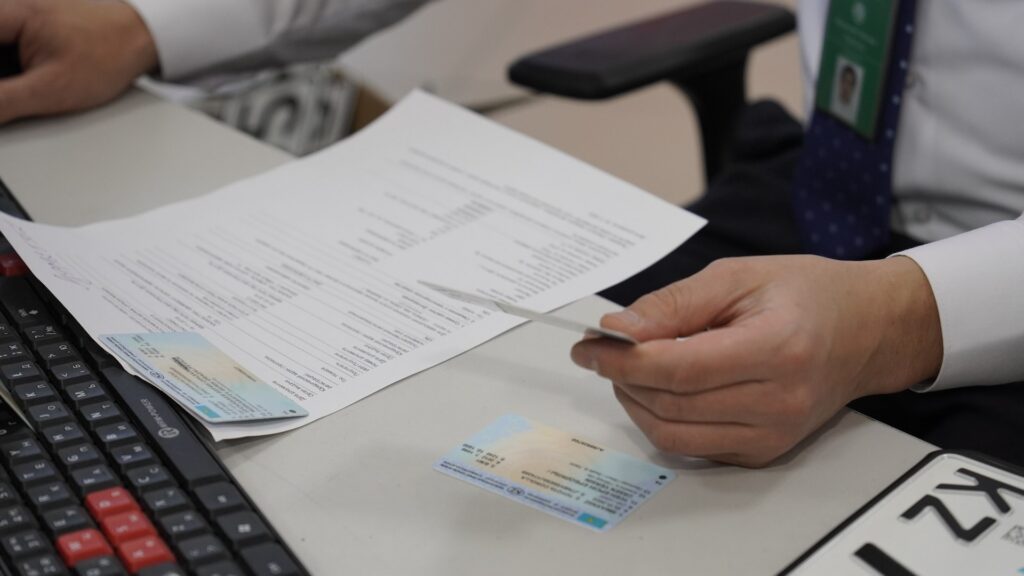 Сотрудник ЦОНа проверяет водительское удостоверение и технический паспорт автомобиля