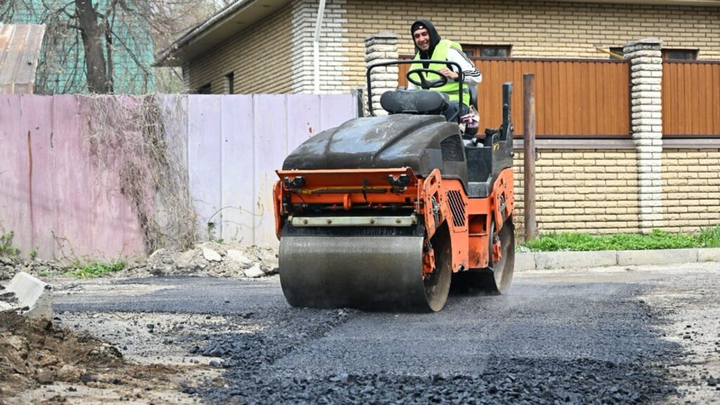 Рабочий на катке укладывает асфальт