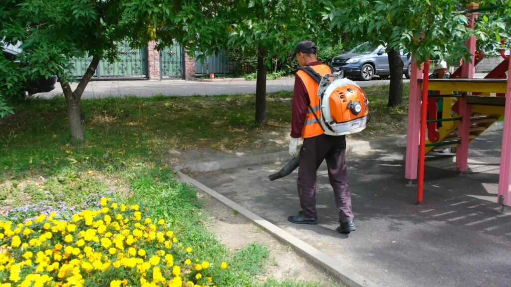 Дворник убирает мусор с детской площадки