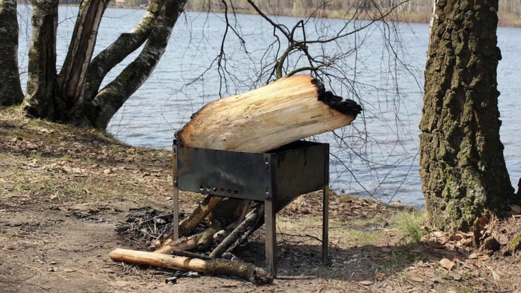 Большое тлеющее палено лежит в мангале в лесу