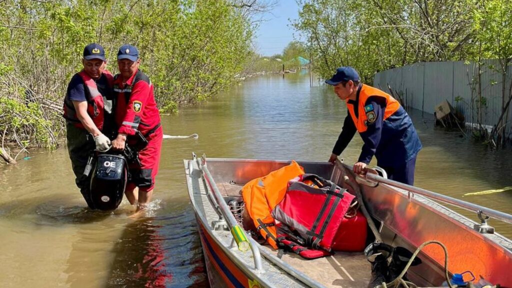 Спасатели по колено в воде с лодкой