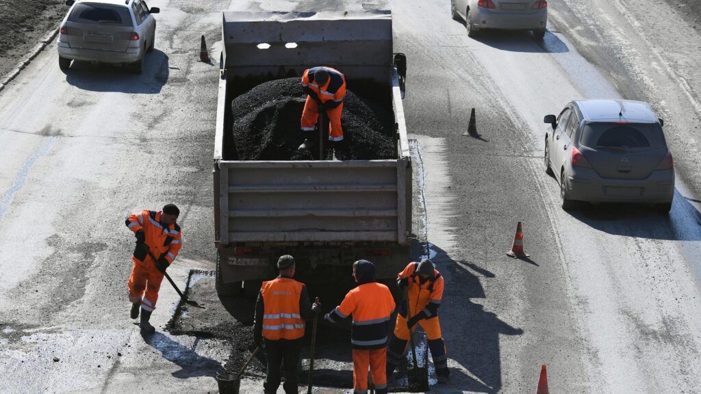 Рабочие выгружают асфальт для ремонта дороги